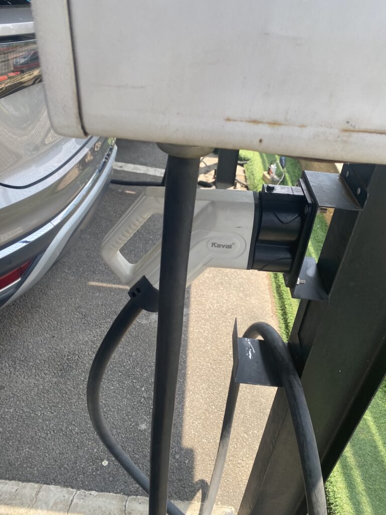 Free-standing EV charging station beside a parked car in Abuja