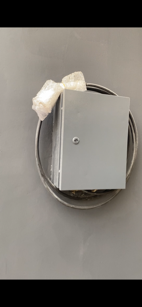 EV charger enclosure fitted to a wall with a coiled charging cable in Abuja