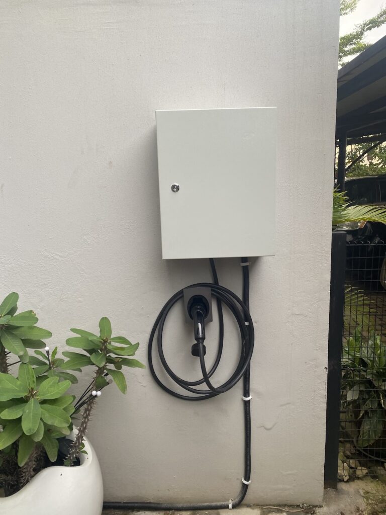 Enclosed EV charger unit and cable mounted on a garden wall in Abuja