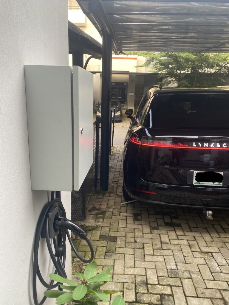 Electric SUV charging from a wall-mounted EV charger in an Abuja compound